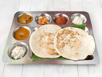 Uttapum servi sur feuille de bananier avec sambar et chutneys